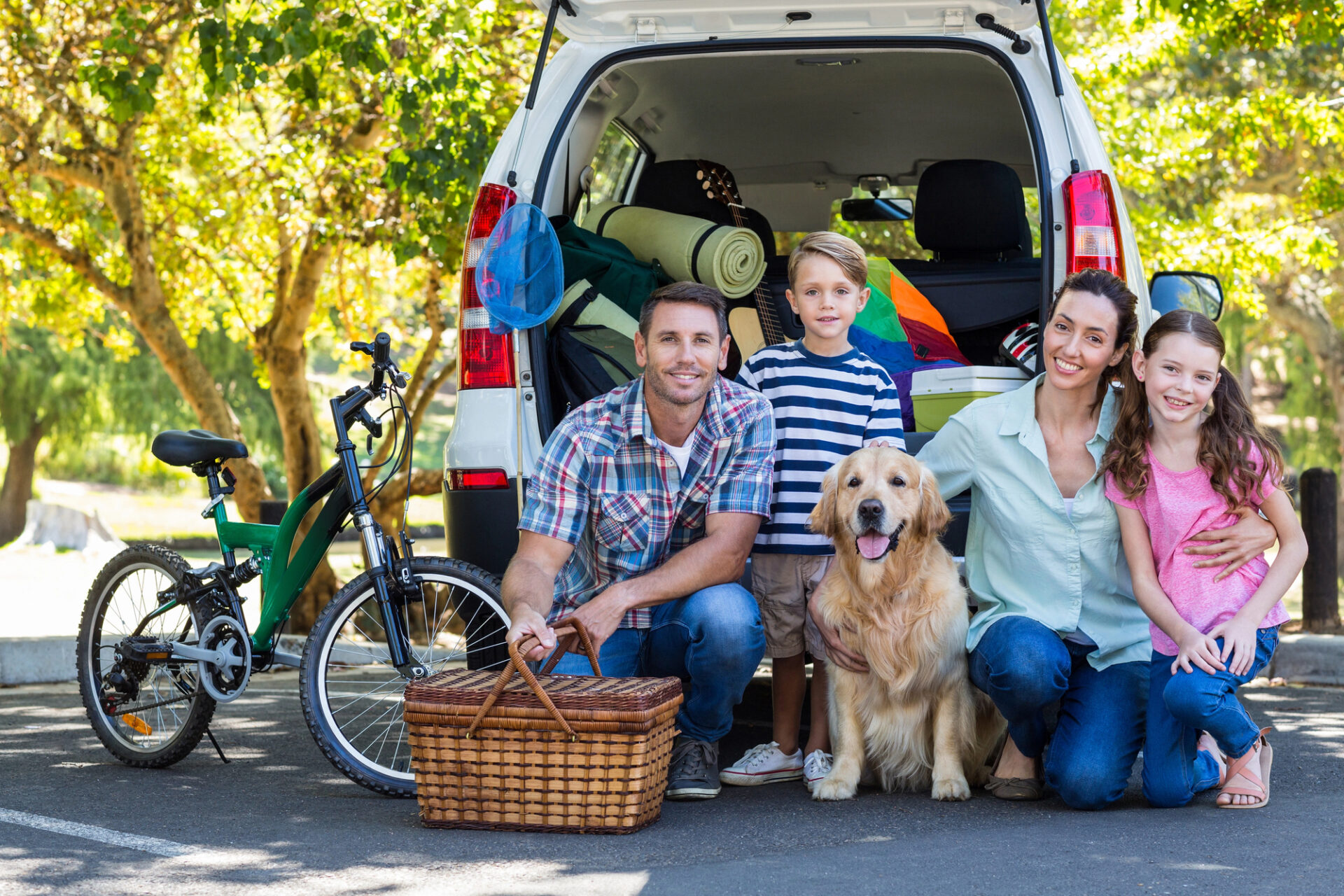famiglia con bambini e cane che carica bagagli nel bagagliaio di un’auto spaziosa per viaggio