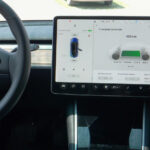 Interni di un’auto tecnologica elettrica con display centrale che mostra stato della ricarica e autonomia.