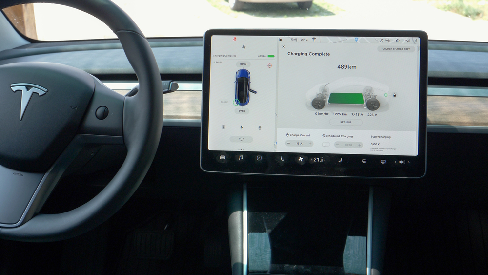 Interni di un’auto tecnologica elettrica con display centrale che mostra stato della ricarica e autonomia.