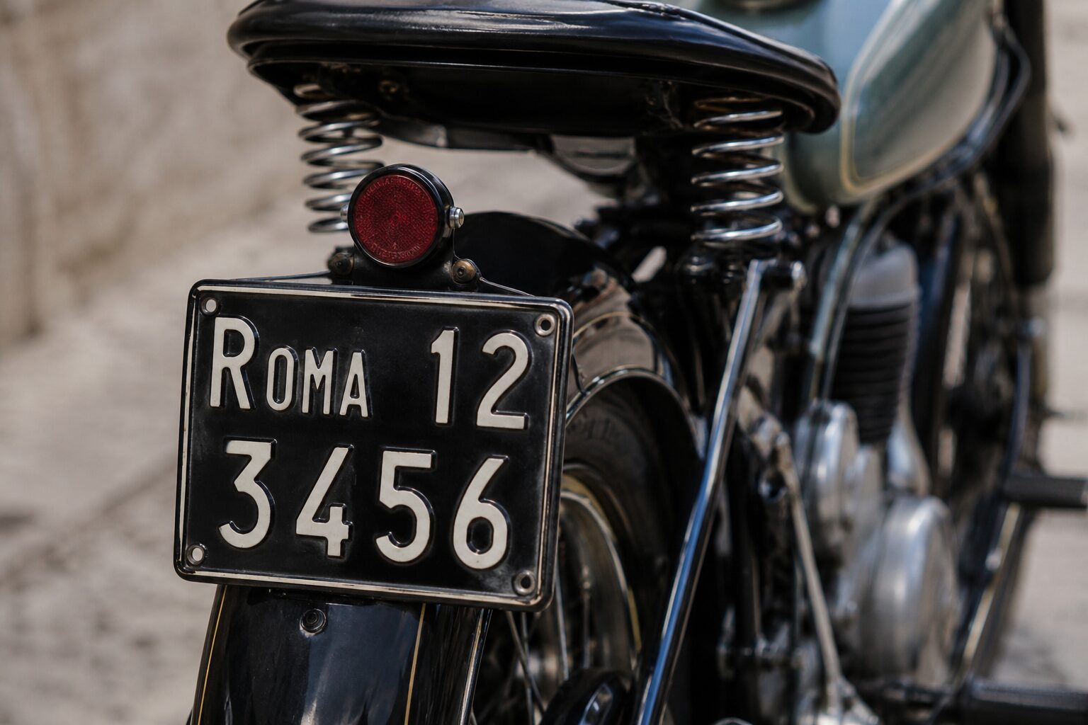 Esempio di targa per moto d’epoca nera con caratteri chiari montata sul retro di una motocicletta storica restaurata.